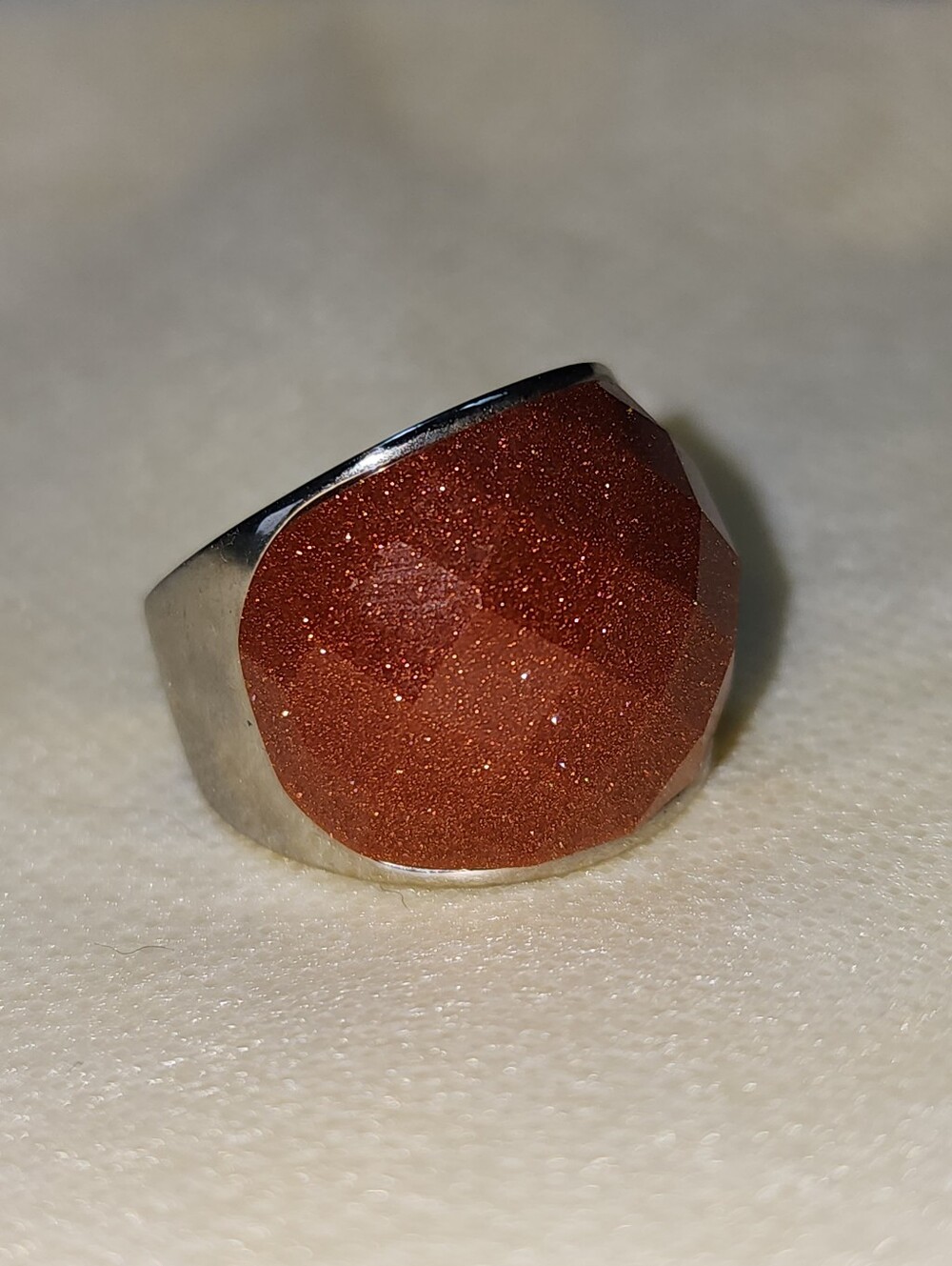 Cocktail ring featuring a faceted orange/brown‎ sandstone gemstone.